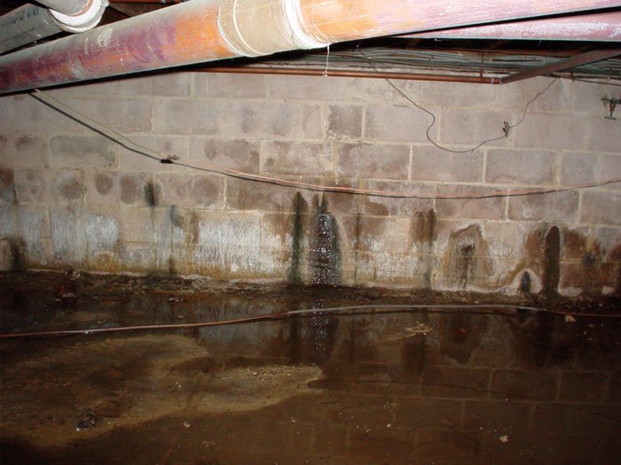 Crumbling and spalling concrete on a deteriorating basement wall surface