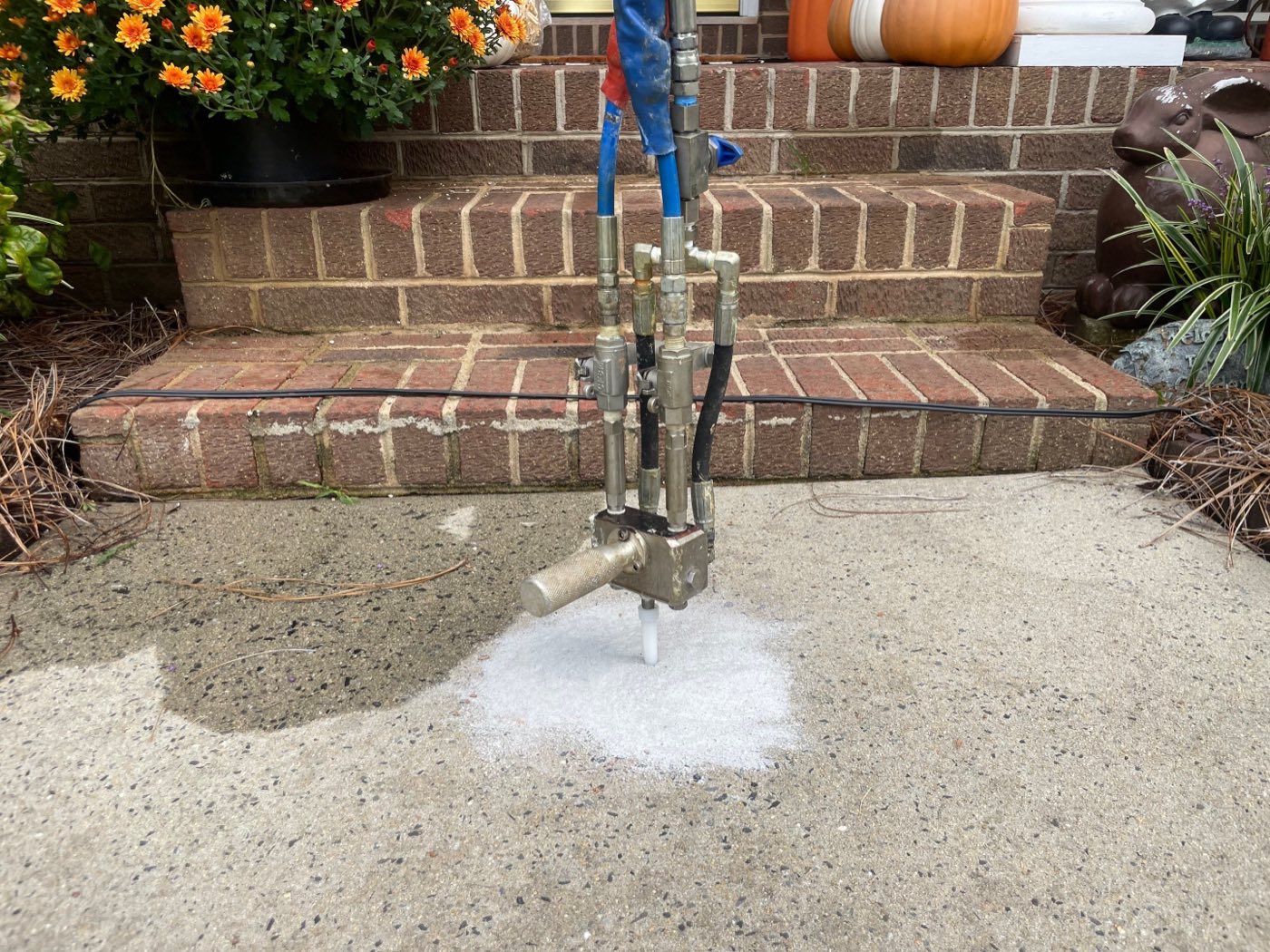 Polyurethane foam being injected through a small port to lift a sunken concrete slab