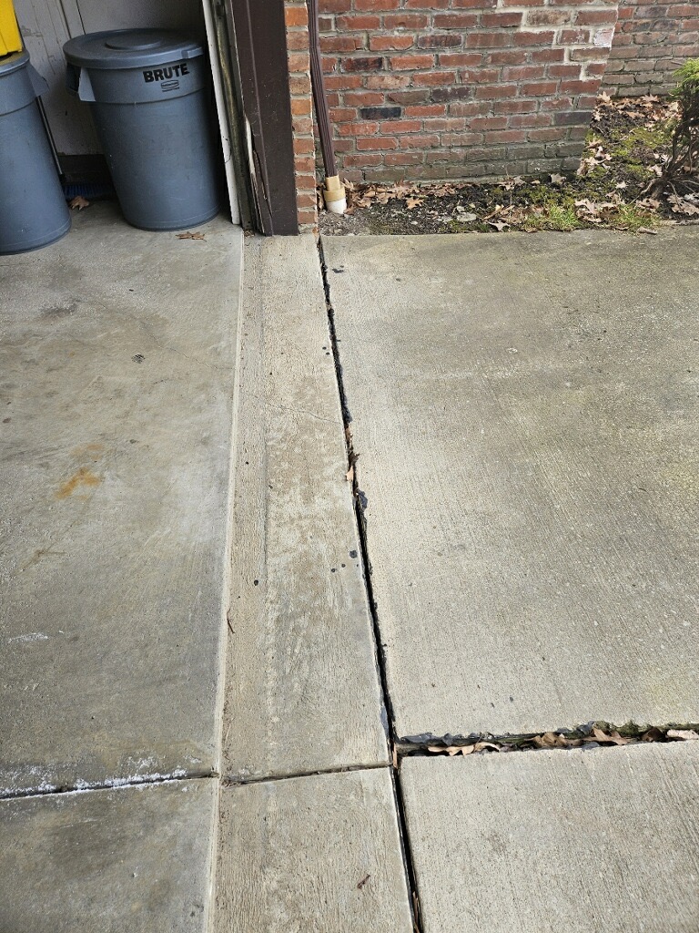 Queen Foundation Repair crew using foam injection equipment to level a sunken residential concrete driveway