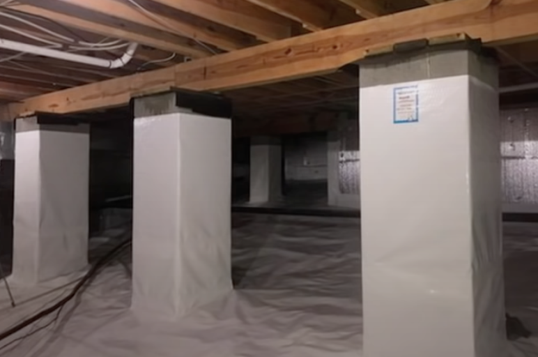New support columns carrying the floor beam in a repaired crawl space