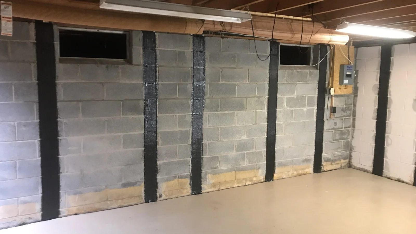 Carbon fiber reinforcement straps installed on a cinder block basement wall to stabilize foundation cracks