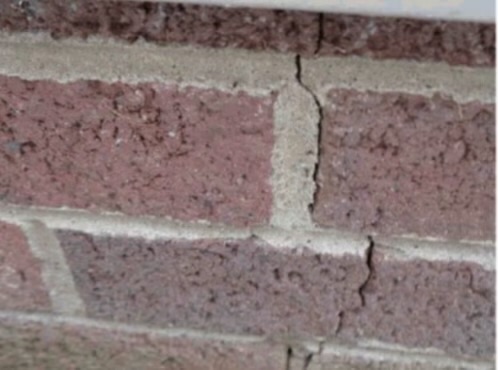 Stair-step crack through the brick and mortar of a settling foundation
