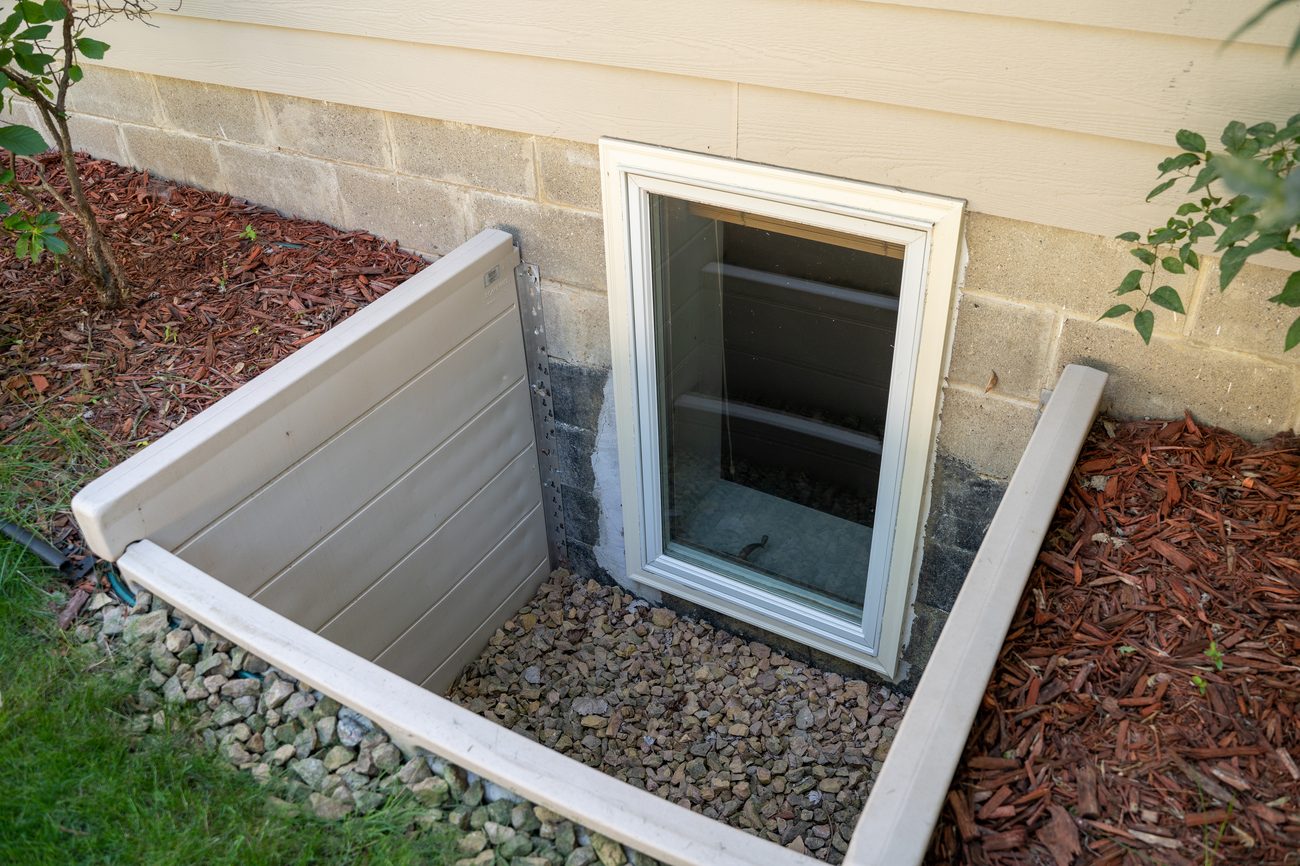 Egress window well installed on exterior of home