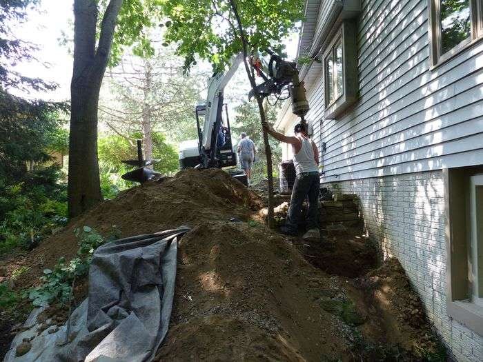 Crew installing foundation piers to stabilize a residential home