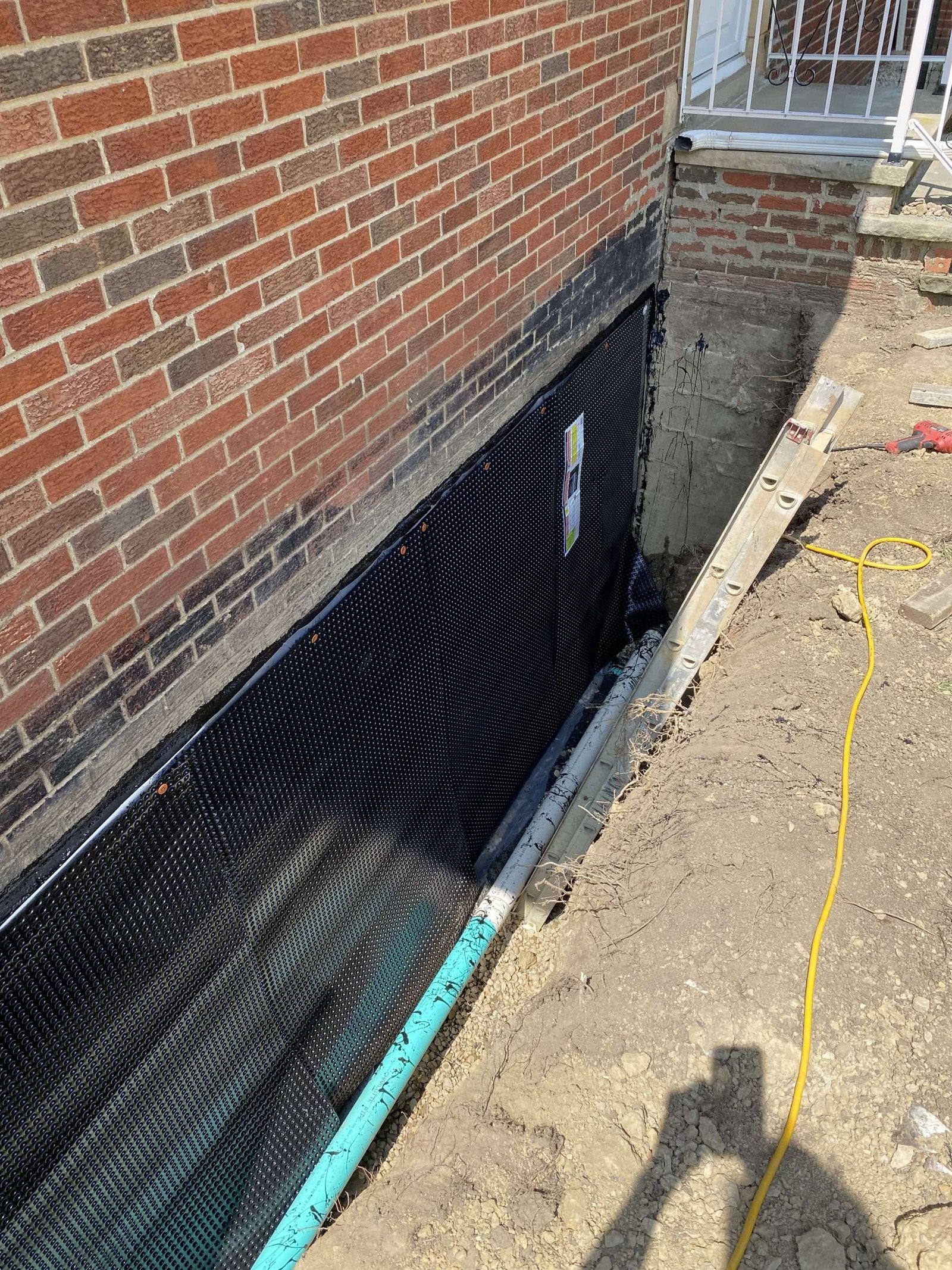 Foundation waterproofing exterior with protective coating and drainage line