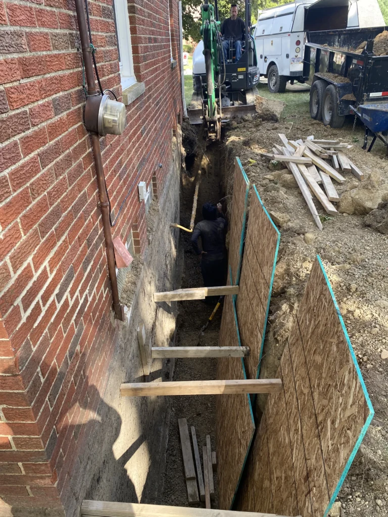 Excavation beside brick foundation wall for local foundation repair and waterproofing work