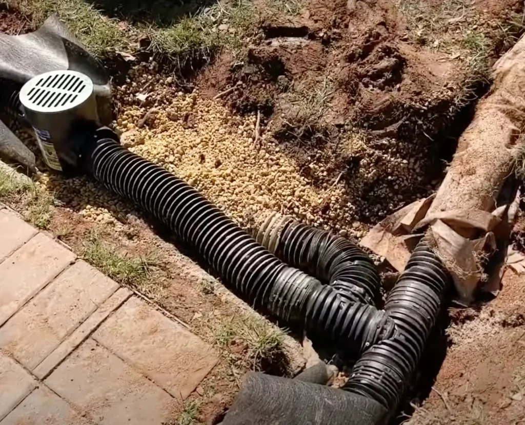 French drain installation with perforated drainage pipe and gravel trench to redirect groundwater