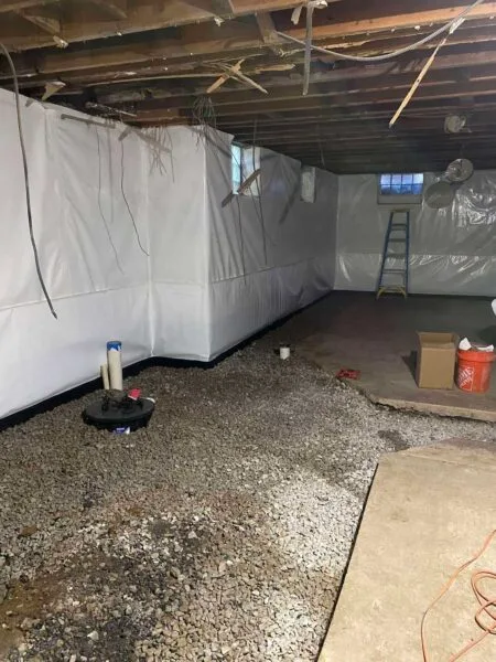 Basement waterproofing system with interior drainage, gravel base, and sump pump installation